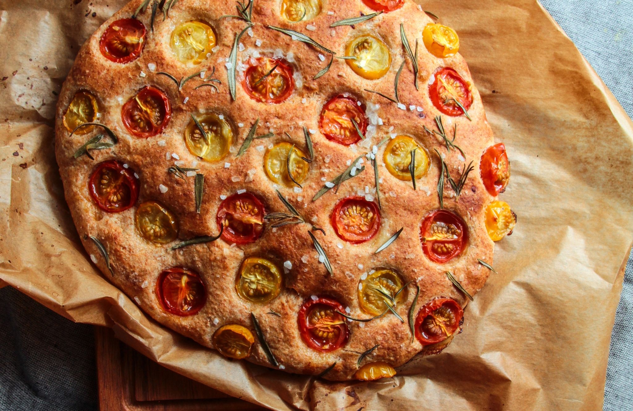 Ein lockerer Hefeteig, der sich nach Lust und Laune belegen lässt: Hier wird die Focaccia ganz klassisch von Tomaten und Rosmarin gekrönt.